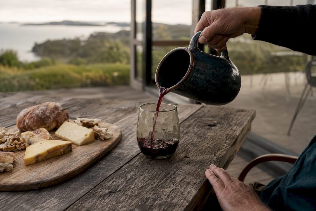 Pouring red wine indoors on Waiheke with a cheese board
