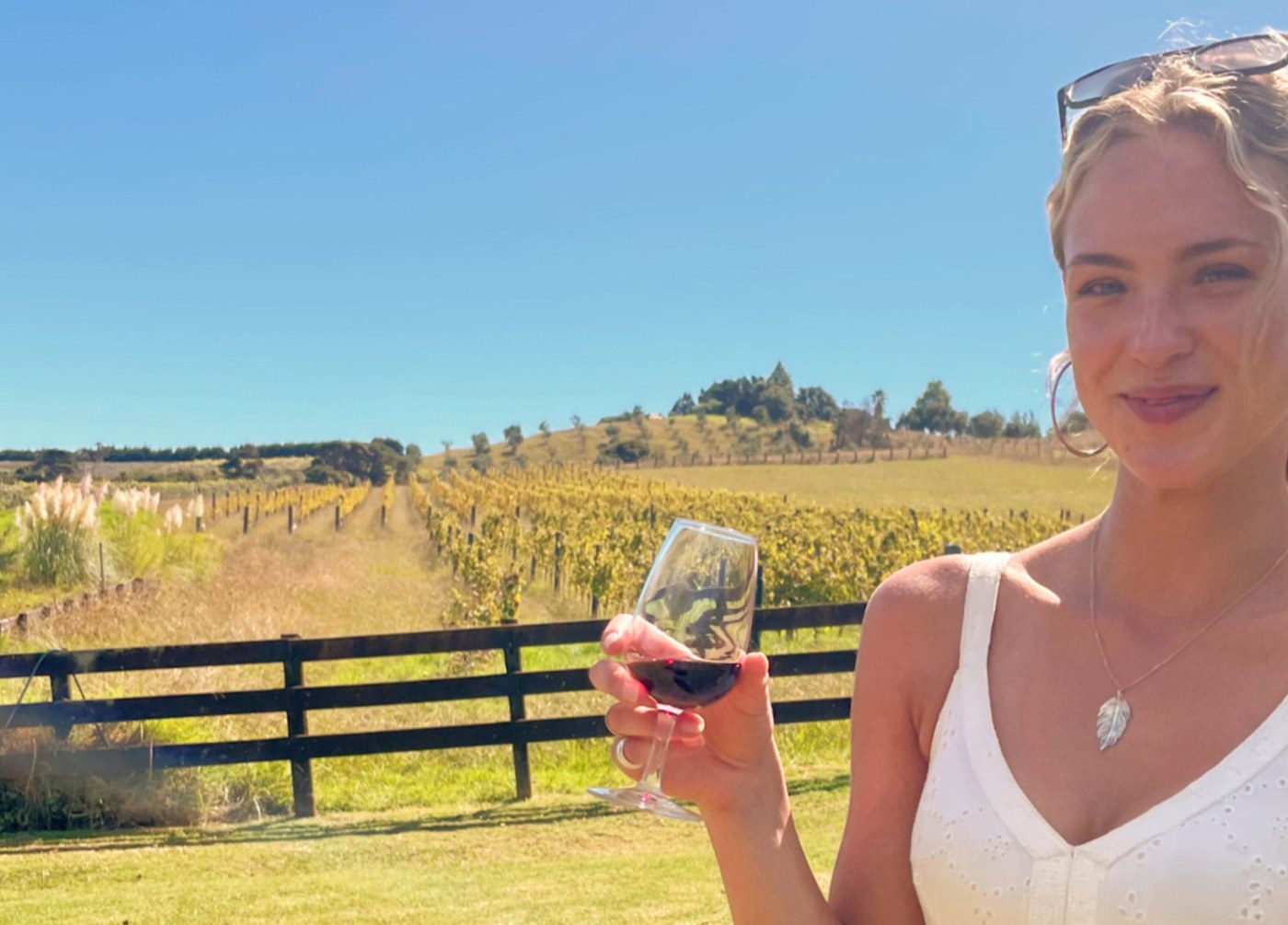 Guest tasting red wine beside a Waiheke vineyard
